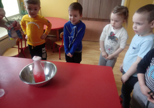 Dzieci obserwują eksperyment z wody, sody i octu